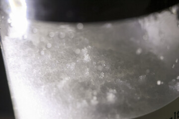Macro close up of white salt crystal with granular texture. common seasoning and cooking ingredient, sodium chloride against dark background in container