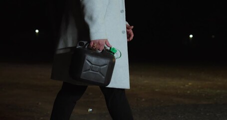 A man carries a fuel can to his car after running out of gas. Concept of car breakdown, emergency, and refueling at night. - Powered by Adobe