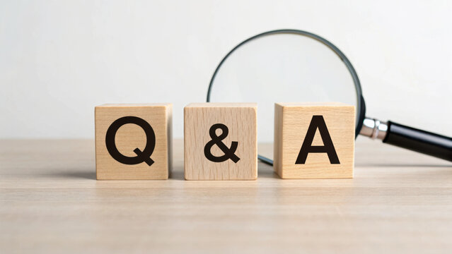 Q and letters on wooden blocks with magnifying glass on table, symbolizing inquiry and detailed examination