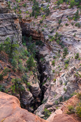 A narrow canyon cut deep into the desert rock reveals dramatic layers and winding formations, highlighting the rugged terrain surrounding Angel’s Landing in Zion National Park.