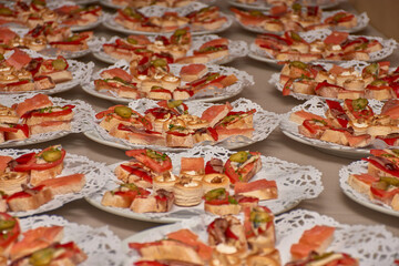 Plates of decorative appetizers ready to be served at a large celebration in an elegant and well-organized setting.