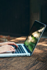 Vertical Horizon Close up businesswoman hand typing laptop drink black coffee cup in green garden...