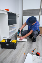Fototapeta premium Man assembling new flat pack furniture using a cordless drill at home