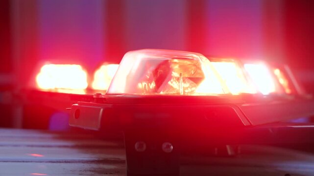 Closeup view of a red emergency vehicle light bar shining on a dark blurred background, ideal for security, safety, alert systems and law enforcement themed stock visuals
