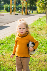 Little caucasian girl holding a stuffed toy in a park. Childhood innocence and growth concept. Happy child playing outdoor.