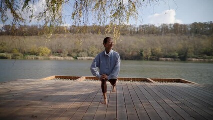 A Korean woman showcases her exercise skills with elegance on a peaceful lakeside platform. The calm water reflects her movements in the afternoon sun.
