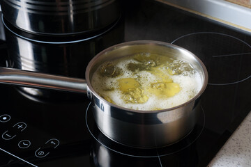 Close-up of fresh yellow potatoes are cooked in a pot of boiling water.