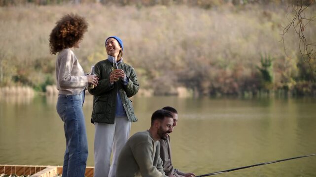 Four friends gather at a beautiful lakeside dock, sharing laughter while fishing under the warm sun in autumn.
