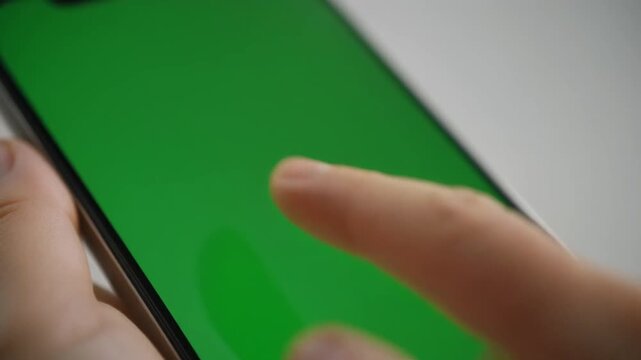 extreme close-up of a thumb performing a slow, deliberate swipe-up gesture on a completely green screen smartphone mockup. perfect for ui/ux demos.