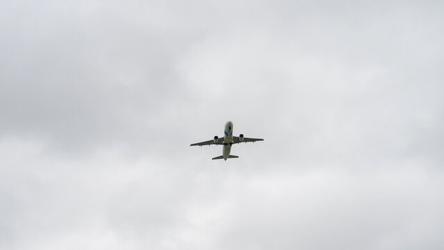 A large airplane is flying through a cloudy sky. The sky is overcast and the plane is the only object visible