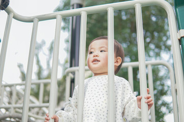 Obraz premium A toddler in a white outfit plays on a playground slide.