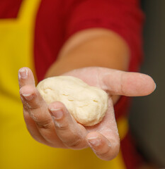 A person is holding a dough ball in their hand