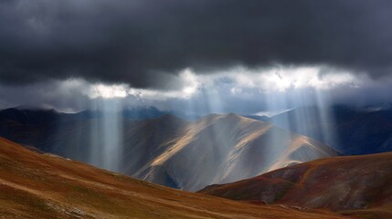 sunbeams. Sunbeams breaking through dark storm clouds over a mountain range, illuminating slopes. travel magazines, destination branding, designed for travel destination branding.