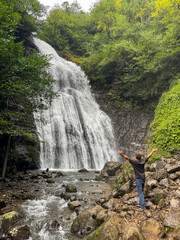 A man standing in front of a waterfall