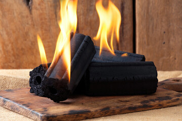 Burning Hexagonal Charcoal Briquettes with Flames on Wooden Board