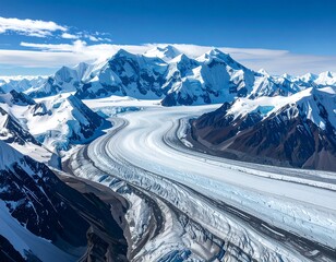 Aerial shot of glacial ice flowing between snow-capped mountain peaks
