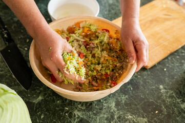 Adult preparing fresh vegetable salad mixing ingredients by hand