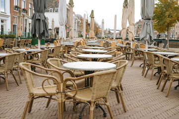 Outdoor cafe with empty wicker chairs and tables on a brick patio in european street setting