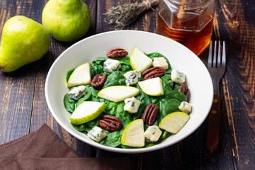Salad with spinach, blue cheese, pear, and nuts. Healthy eating. Vegetarian food.
