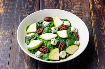 Salad with spinach, blue cheese, pear, and nuts. Healthy eating. Vegetarian food.
