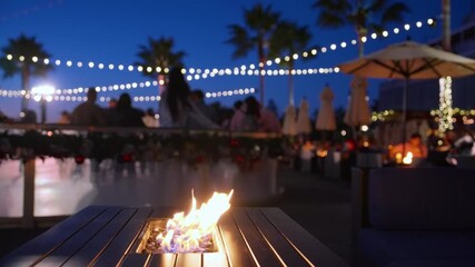 sunset waterfront lounge with diverse guests string lights and palm silhouettes frame lively social scene - Powered by Adobe