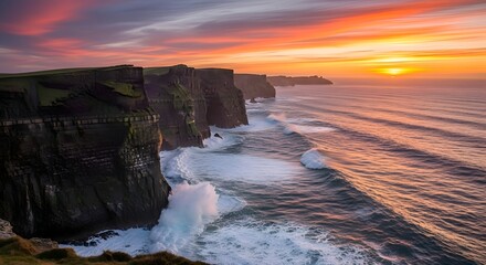 Obraz premium Dramatic sunset over rugged coastal cliffs with crashing waves, Irish landscape
