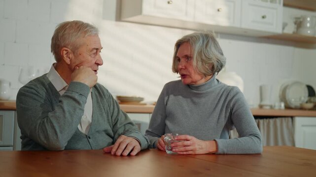 Healthy senior people communicating in home kitchen, old married couple portrait . Worried woman and her husband talking about health in old age, grey-haired caucasian people, happy married couple