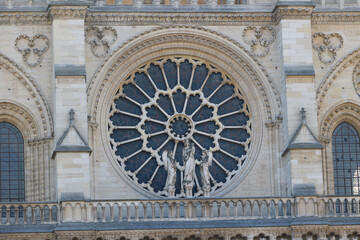 Close-up view of the rose window and stone sculptures on the facade of Notre Dame Cathedral in Paris, France.