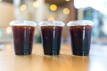 A trio of iced Americano coffee drinks set on a table in a cozy café environment.