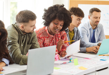 Young office diverse colleagues sitting in boardroom at desk with laptop to brainstorm, discuss, plan financial statistics together, multiracial coworkers cooperating working at meeting on strategy