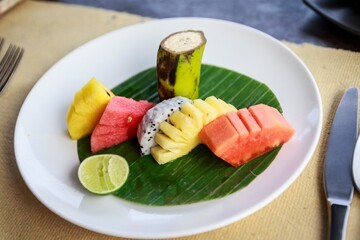 Tropical Fruit Platter on Banana Leaf with Lime and Utensils in Breakfast Setting