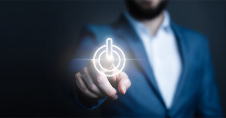 Professional hand pointing at a glowing power on/off button on a dark background. Concept of startup, activation, beginning, and energy control.