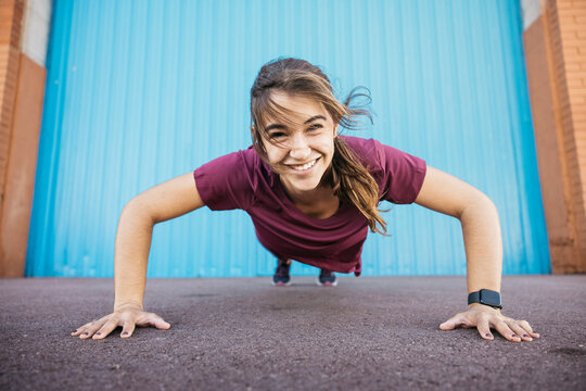 Happy woman performing push-up exercise outdoors training hard