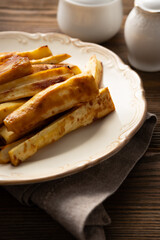 Roasted parsnips roots slices with herbs wooden table