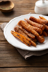 Roasted baby carrots roots with herbs wooden table