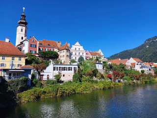old buildings and green embankment of town Frohnleiten under blue sky at sunny day. Austria