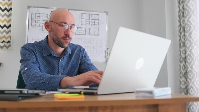 focused architect reviewing blueprints, silent studio with architect designing plans efficiently, an architect in quiet studio carefully reviewing blueprints and taking notes during morning hours