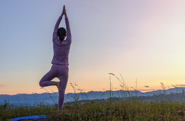 Fitness girl practicing yoga on mountain sunset sky background