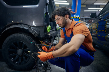 Mechanic repairing car wiring in auto workshop