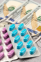 Dollar bill and a set of medicine pills. Rising costs of medical care. Reliefs for buying medicine.Pills in capsules scattered on US dollars currency.Concept of health care in USA.