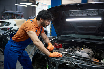 A mechanic is expertly repairing a car engine in a professional garage workshop setting
