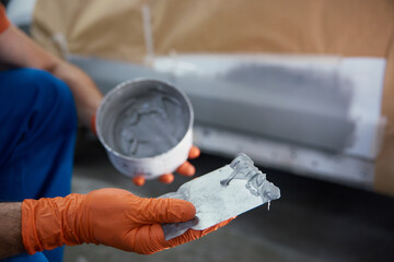 Closeup of technician is meticulously prepping a car panel with primer in a garage workshop