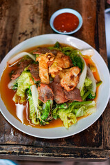 Thai street food sukiyaki soup with dipping sauce on wooden tabl