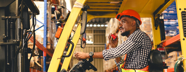 warehouse, radio, and forklift in shipping warehouse. Male transport worker in safety uniform transport worker talking on walkie talkie, drives forklift at freight cargo warehouse port. © bigy9950