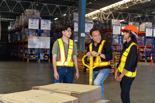 Asian warehouse workers inspect goods on pallet trucks in storage warehouse.