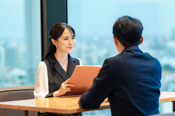 高層階のレストランまたはカフェで、男女がテーブル越しに向かい合って会話しているシーン