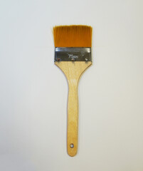 Flat paint brush on a white background. Wide bristles, wooden handle, 75 mm size, insulated object.