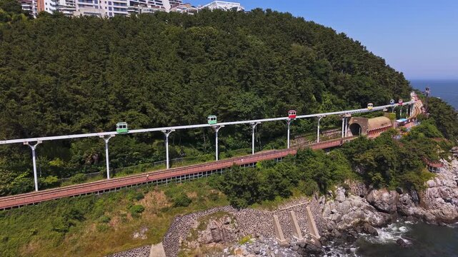 Drone flying along the Haeundae Sky Capsule rail in sunny Busan, South Korea