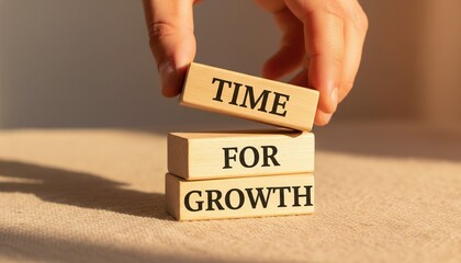 Hand stacking wooden blocks spelling TIME FOR GROWTH, a conceptual image for business development and personal growth.