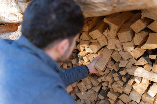 Man stacking firewood in woodpile preparing for winter